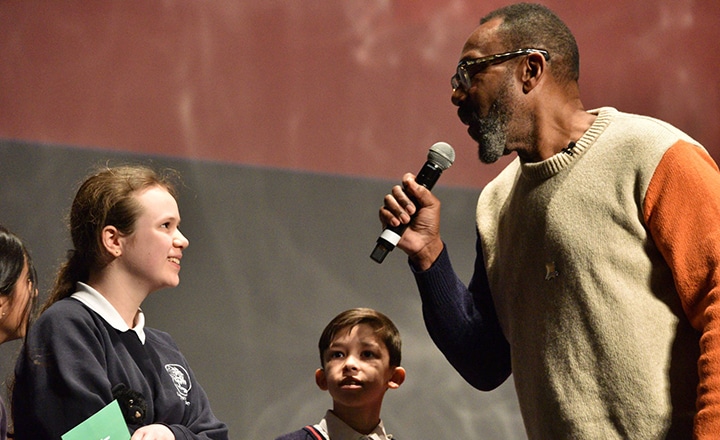 Image of Lenny Henry with a microphone talking to a young person