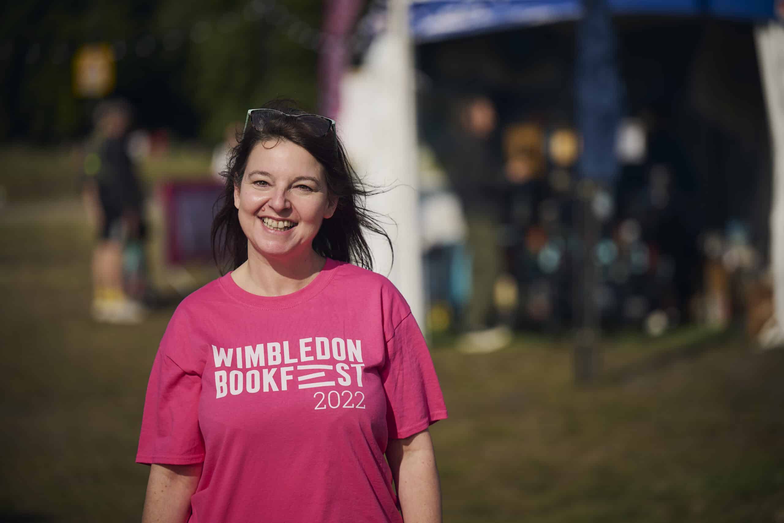 A Staff member in a Wimbledon Book Fest pink T-shirt smiling into the camera