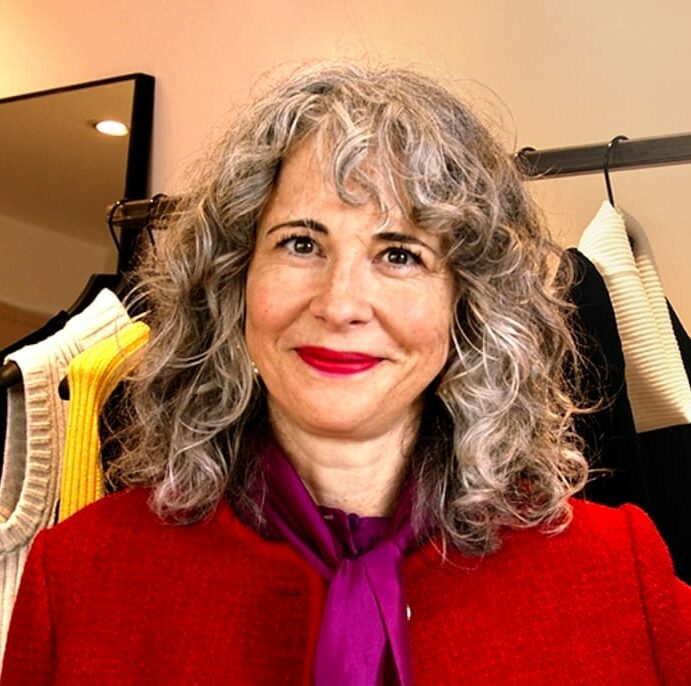 Image of Anna Murphy with her hand on her hip wearing a bright red jacket and purple silk shirt