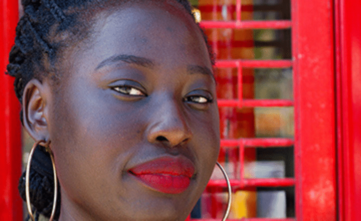 A close up of a woman with red lipstick and hoop earrings and braided hair