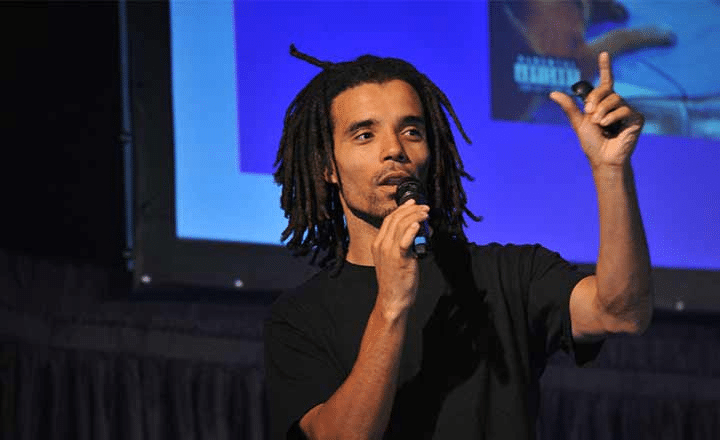 A Man with braids talking into a microphone