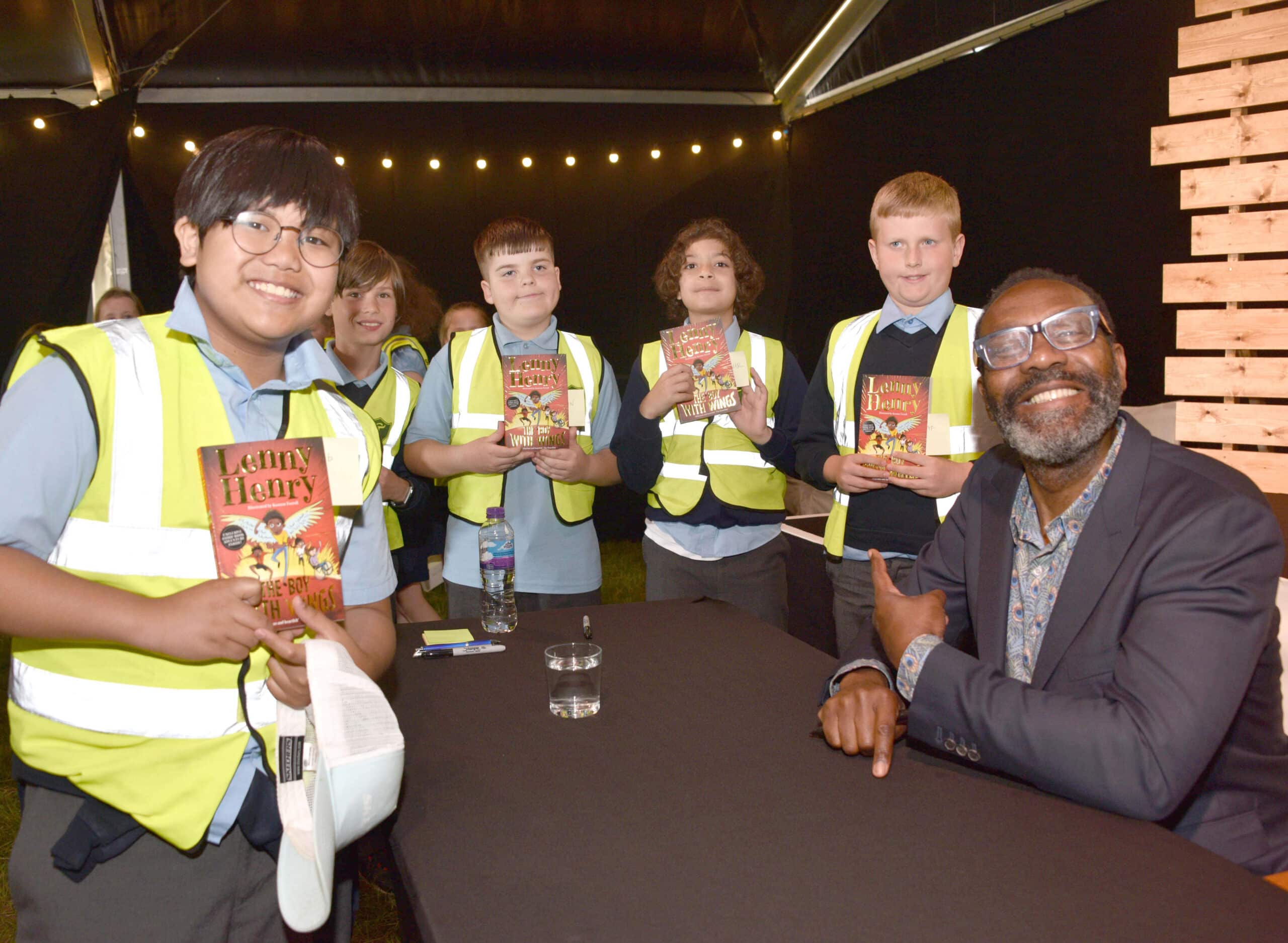 Group of school children wearing Hi-Viz jackets with Lenny Henry smiling